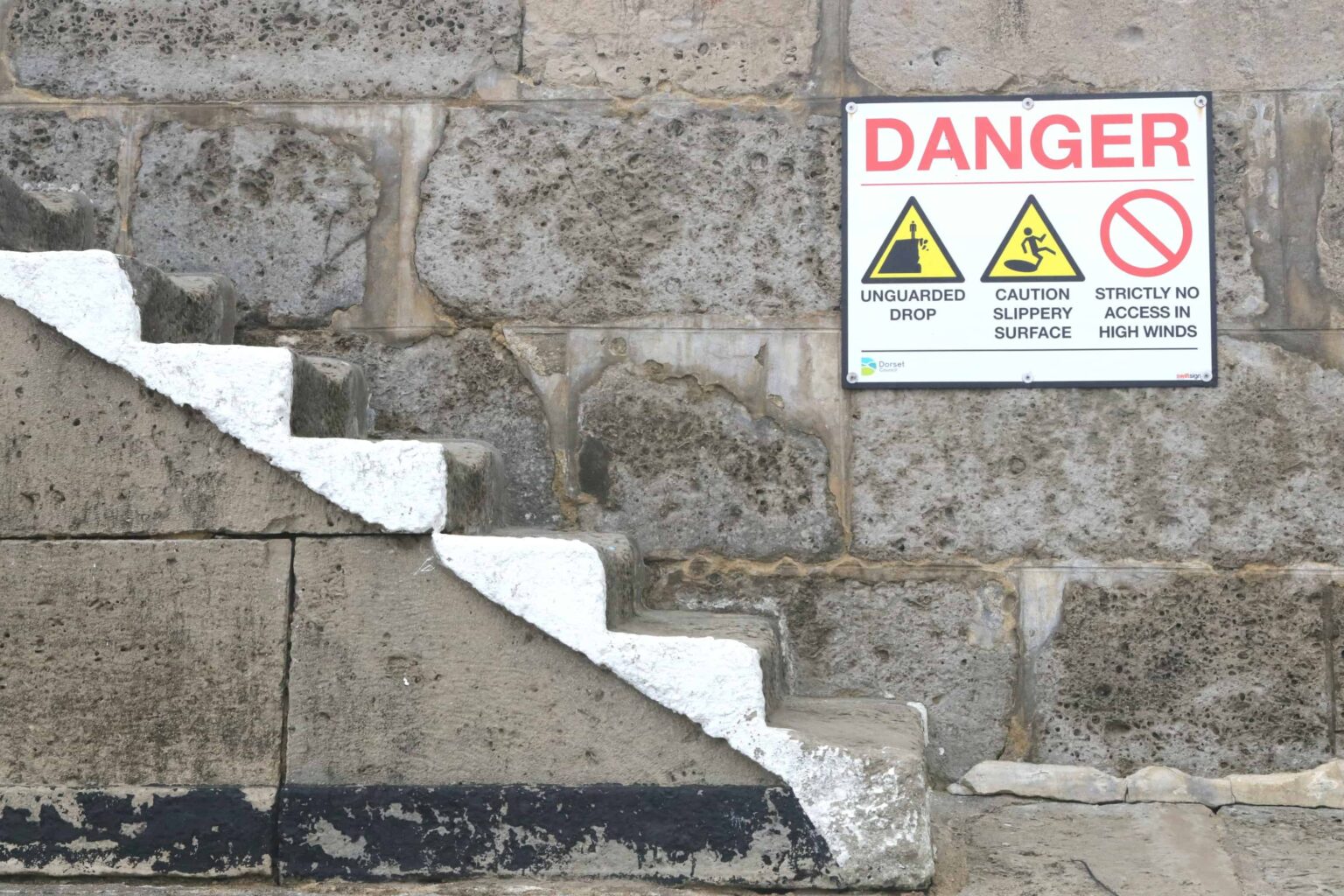 una señal en un muro de piedra que advierte de un peligro